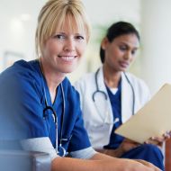 Blonde female physician sitting down in scrubs 
